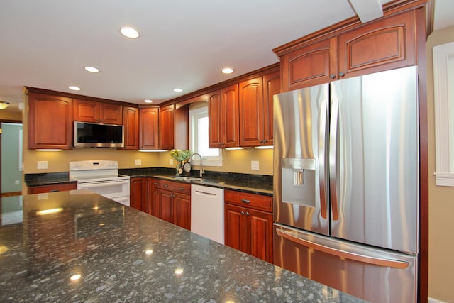 kitchen featuring recessed lighting, appliances with stainless steel finishes, dark stone counters, and a sink