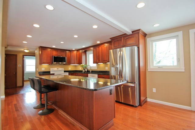 kitchen with light wood-type flooring, beam ceiling, a center island, recessed lighting, and stainless steel appliances