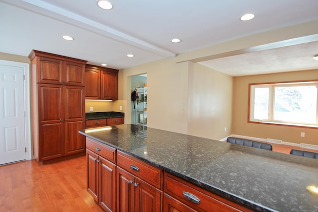 kitchen with light wood-type flooring, beamed ceiling, visible vents, dark stone countertops, and recessed lighting