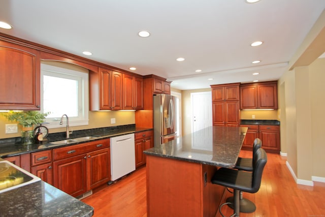 kitchen with a sink, light wood-style floors, stainless steel refrigerator with ice dispenser, and white dishwasher