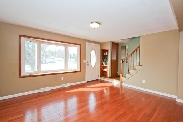 entryway with visible vents, light wood-style flooring, stairway, and baseboards