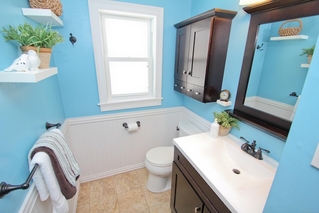 half bath featuring a wainscoted wall, toilet, and vanity