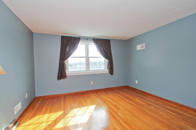 unfurnished room with visible vents, baseboards, and wood finished floors