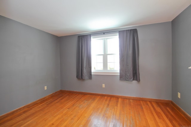 empty room with baseboards and light wood-type flooring