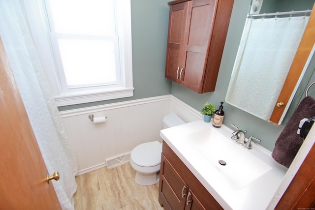 bathroom featuring visible vents, toilet, wainscoting, wood finished floors, and vanity