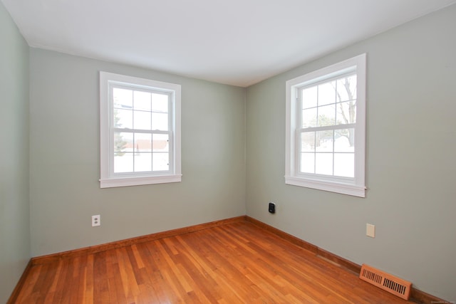 empty room featuring visible vents, plenty of natural light, light wood-style floors, and baseboards