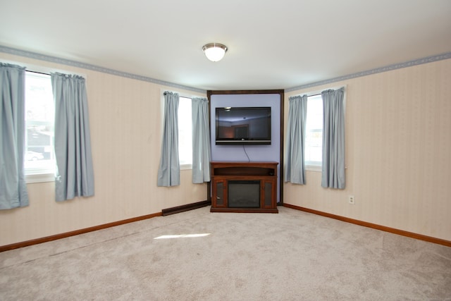 unfurnished living room featuring baseboards, a fireplace, wallpapered walls, and carpet