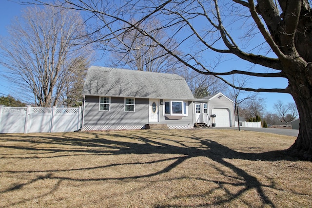 view of front facade featuring fence, driveway, a shingled roof, entry steps, and a front lawn