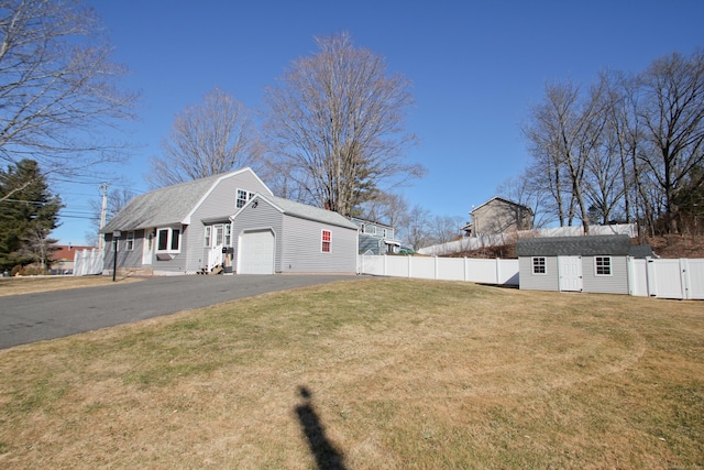 exterior space with fence, aphalt driveway, an outdoor structure, a garage, and a gate