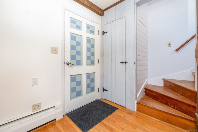 foyer entrance with a baseboard radiator, stairs, and light wood-style flooring