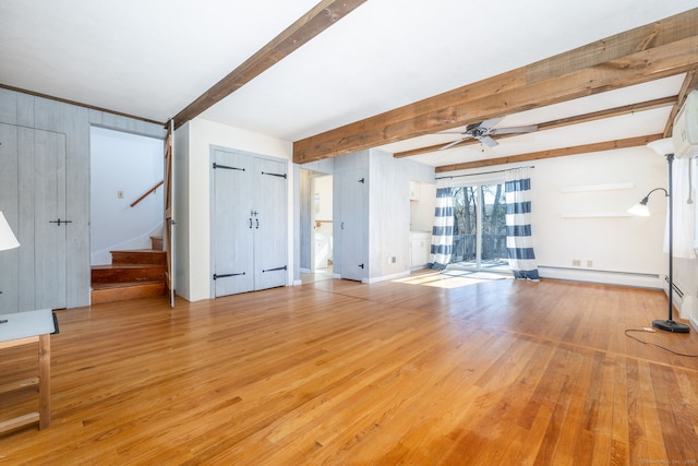 unfurnished living room with a ceiling fan, wood finished floors, stairs, baseboard heating, and beam ceiling