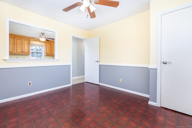 unfurnished room with ceiling fan and baseboards