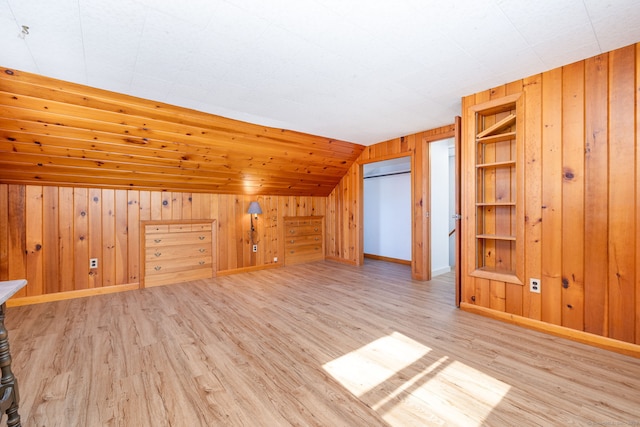 bonus room with lofted ceiling, wood walls, built in features, and light wood-style floors