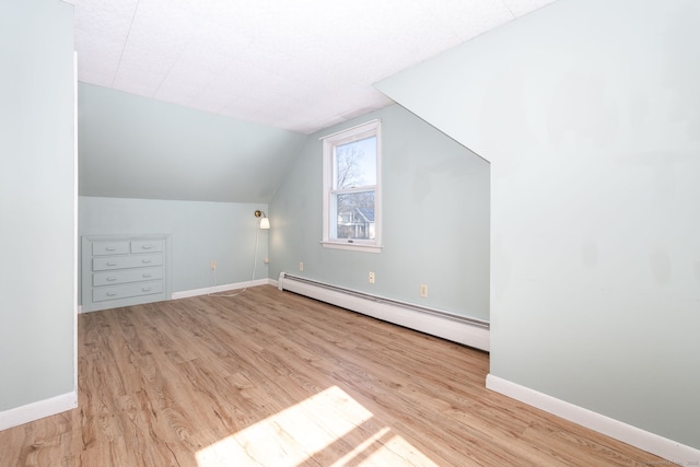 bonus room featuring a baseboard heating unit, vaulted ceiling, baseboards, and wood finished floors