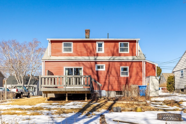 snow covered rear of property with a deck