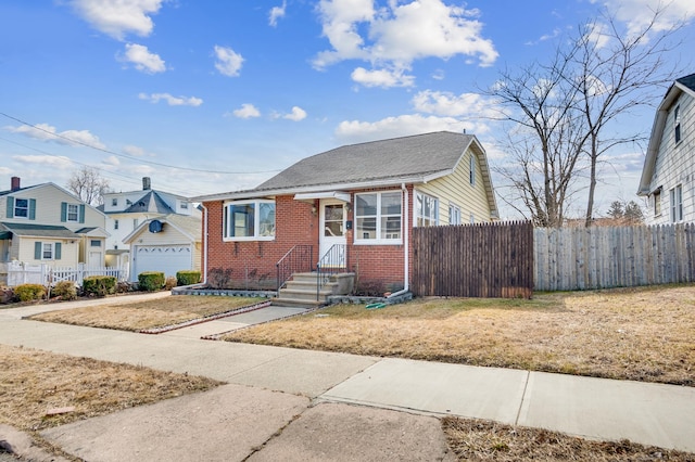 bungalow-style home featuring a garage, fence, and brick siding