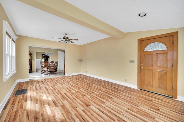 foyer featuring light wood finished floors, beamed ceiling, visible vents, and baseboards