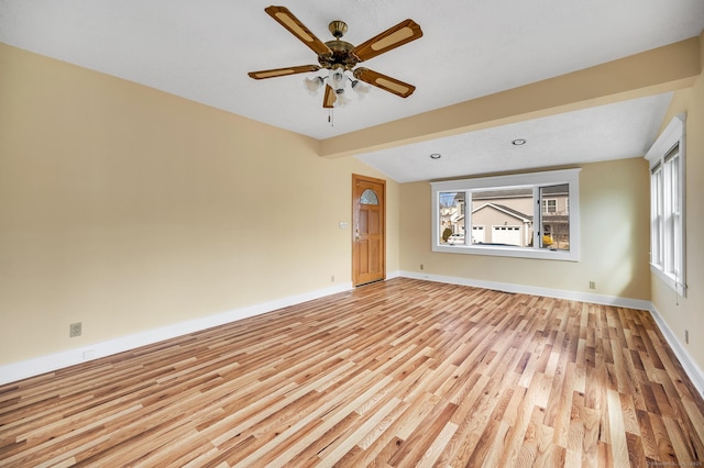 spare room with light wood-style flooring, ceiling fan, lofted ceiling with beams, and baseboards