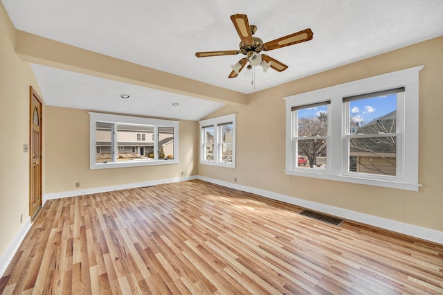 unfurnished room with lofted ceiling, light wood-style flooring, visible vents, and baseboards