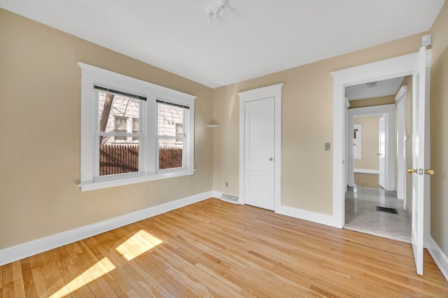 unfurnished bedroom featuring light wood-style floors, visible vents, and baseboards