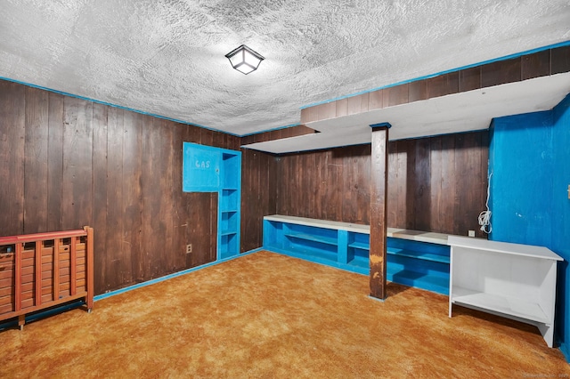 unfurnished bedroom featuring carpet floors, wooden walls, and a textured ceiling