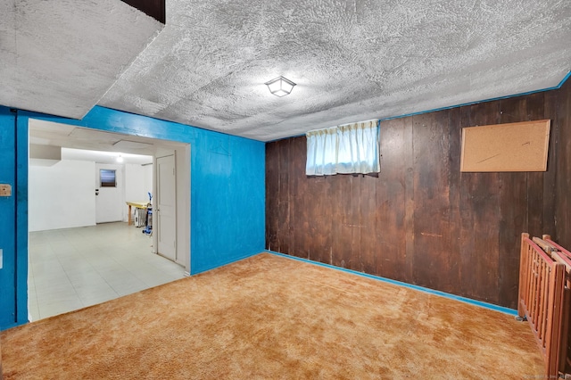 basement with carpet, wooden walls, and a textured ceiling