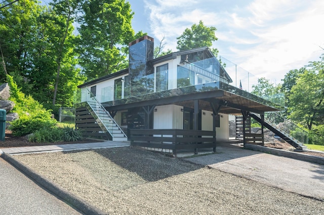 view of front facade with stairs, a chimney, and a wooden deck