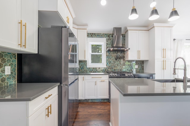 kitchen featuring dark countertops, freestanding refrigerator, white cabinets, and wall chimney range hood