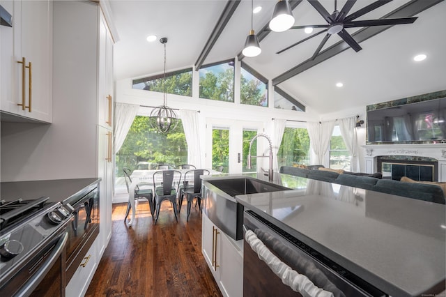 kitchen with dark countertops, white cabinets, a sink, and gas stove