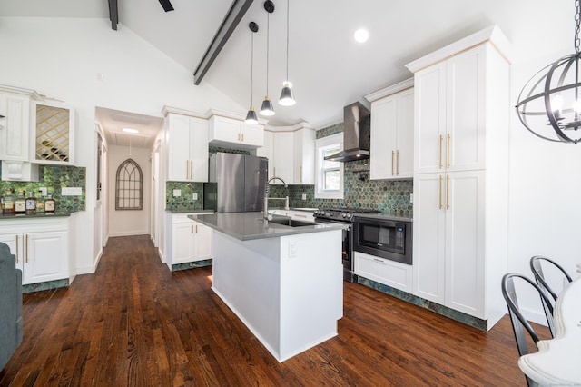 kitchen featuring wall chimney exhaust hood, hanging light fixtures, an island with sink, and stainless steel appliances