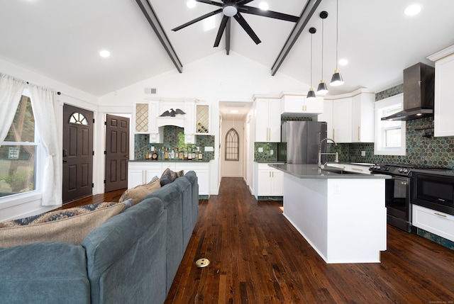 kitchen featuring electric stove, freestanding refrigerator, open floor plan, wall chimney range hood, and an island with sink