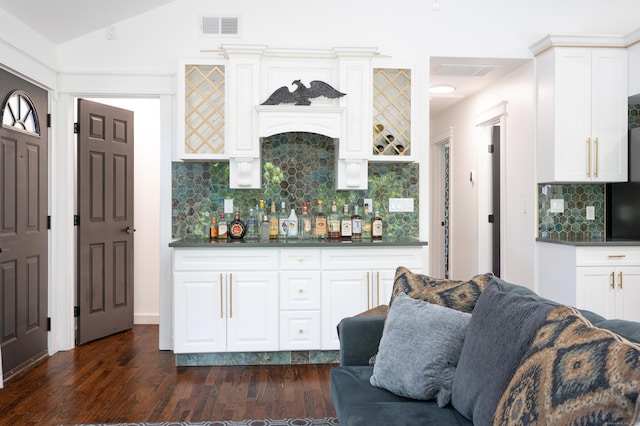 living room with lofted ceiling, dark wood-style floors, visible vents, and a dry bar