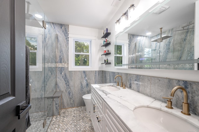 full bath with toilet, a marble finish shower, tile walls, and a sink