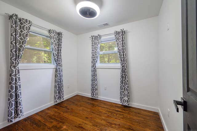 unfurnished room with dark wood-style floors, baseboards, and visible vents