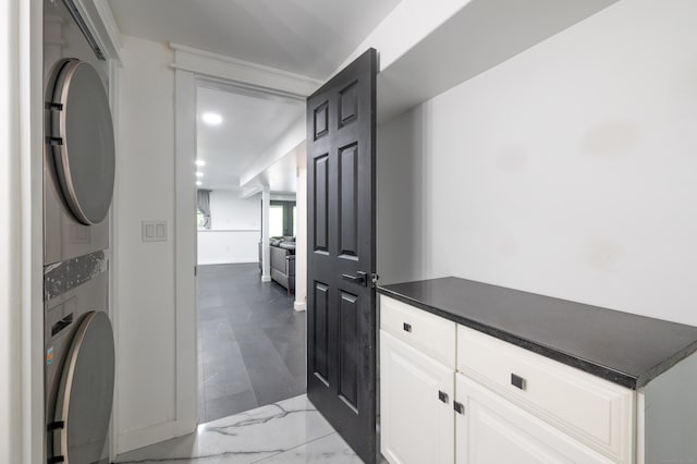 interior space with marble finish floor, recessed lighting, and stacked washer and clothes dryer