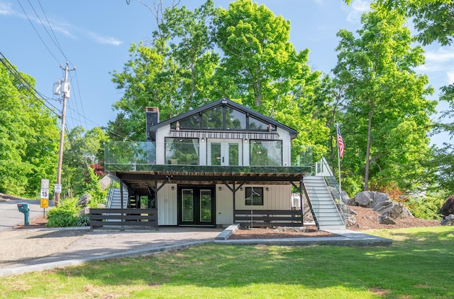 rear view of house featuring a deck, a lawn, a chimney, and stairs