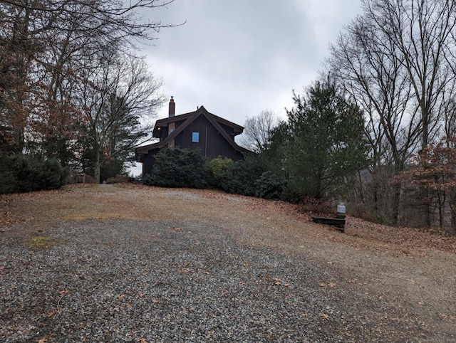 view of property exterior with driveway and a chimney