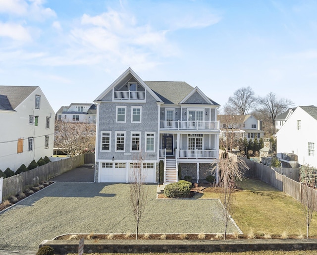 view of front of home with driveway, a balcony, a porch, stairs, and a front lawn