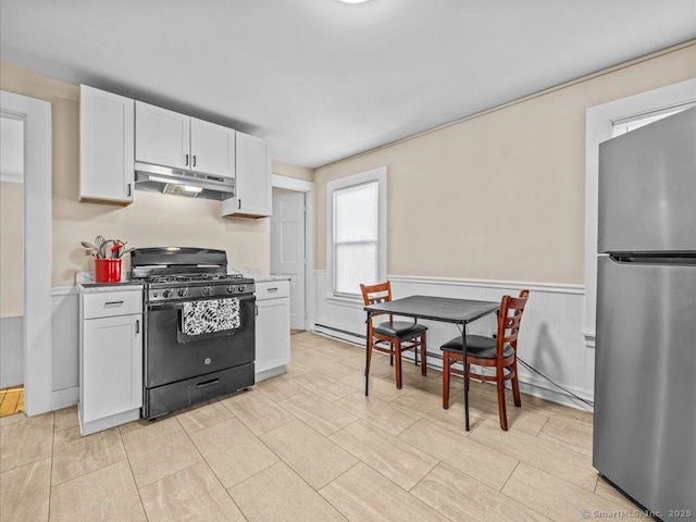 kitchen featuring freestanding refrigerator, light countertops, under cabinet range hood, white cabinetry, and gas stove