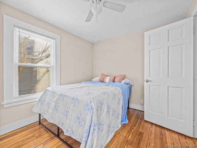 bedroom featuring a ceiling fan, baseboards, and wood finished floors