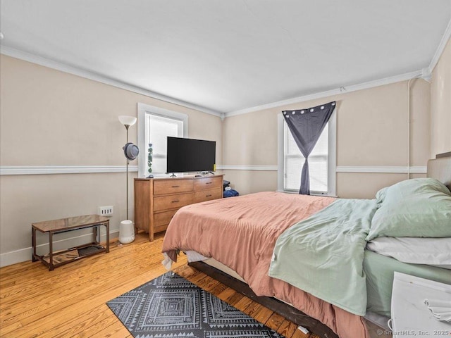 bedroom with crown molding, light wood-style flooring, and baseboards