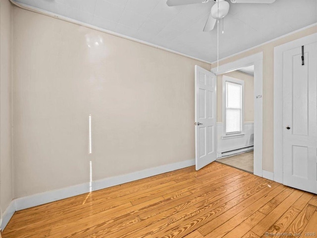 unfurnished room featuring ceiling fan, light wood-style flooring, baseboards, ornamental molding, and baseboard heating