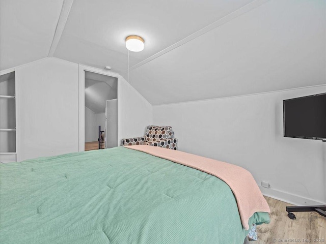 bedroom with lofted ceiling, wood finished floors, and baseboards