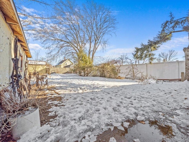 snowy yard featuring a fenced backyard