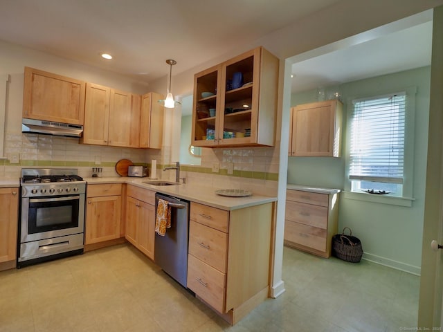 kitchen with under cabinet range hood, light brown cabinets, appliances with stainless steel finishes, and light countertops