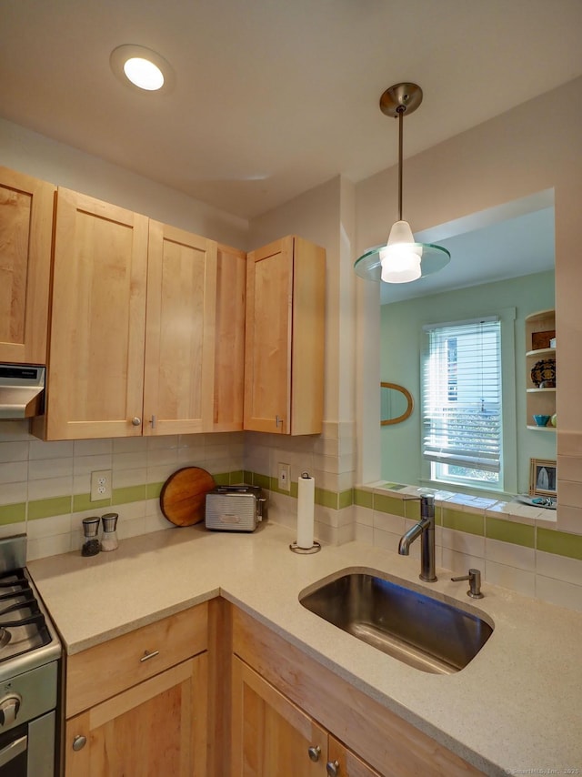 kitchen featuring hanging light fixtures, range hood, light brown cabinetry, a sink, and gas stove