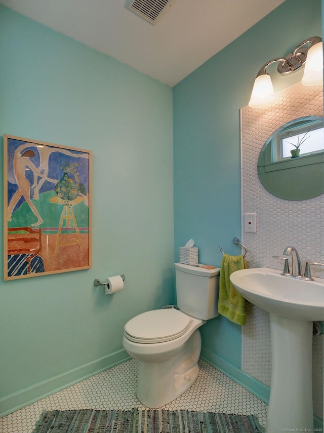 half bath with toilet, baseboards, visible vents, and tile patterned floors