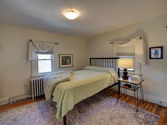 bedroom featuring baseboards, wood finished floors, and radiator