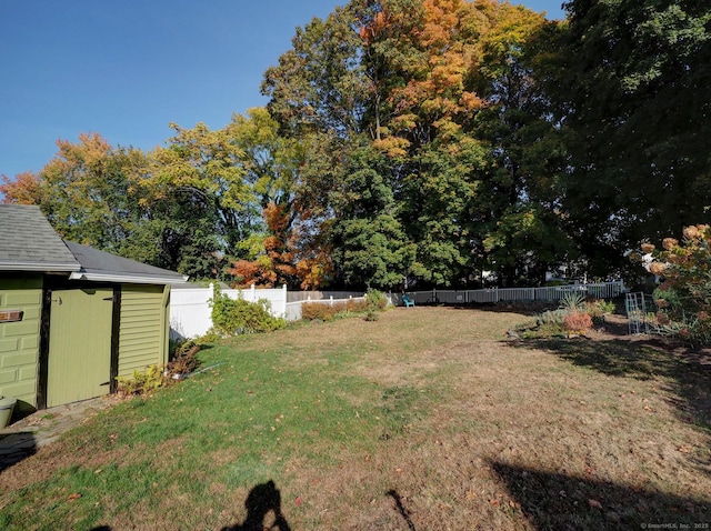 view of yard featuring a storage shed, a fenced backyard, and an outbuilding