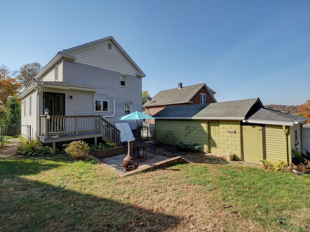 back of house featuring fence, a deck, a lawn, and a patio